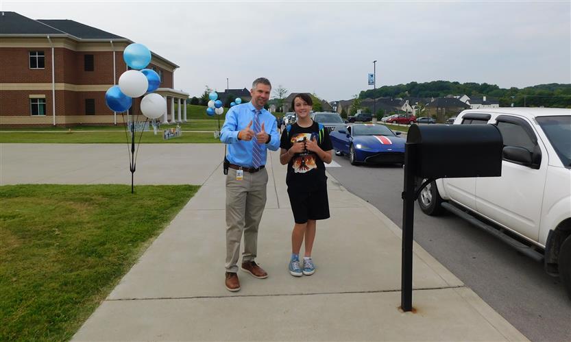 A principal and student give a thumbs up